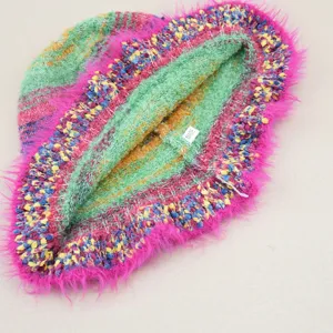 Dettaglio in primo piano della trama arcobaleno colorata e del bordo rosa peluche del berretto.