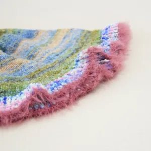 Primo piano dettaglio del berretto lavorato a maglia arcobaleno con morbido bordo rosa.