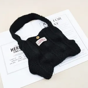Bolso de mano de lana tejida negra con diseño plisado, botón de madera y etiqueta.