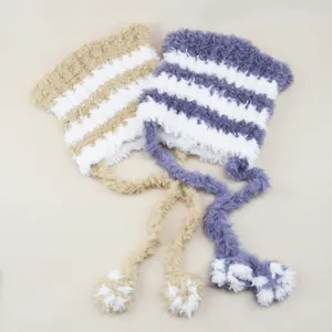 Detailed close-up of fluffy striped winter warm hats with long tassels and cozy pom-poms.