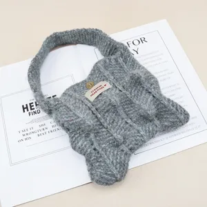 Vista detallada de bolso de punto gris, diseño plisado elegante con etiqueta de tela y botón.