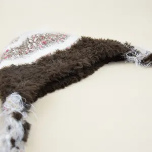 Close-up detail of winter warm knit beanie hat with fluffy brown faux fur and braided tassels.