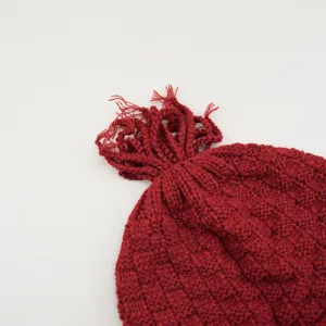 Primo piano del cappello in maglia uncinetto rosso retrò con trecce di nappe, berretto invernale.