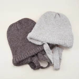 Detailed close-up of cozy wool knit beanie hats with cute strings in chic colors.