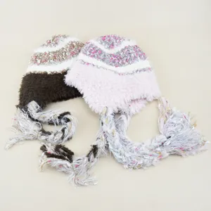 Detailed view of plush knitted winter cap with braided tassel strings in warm colors.