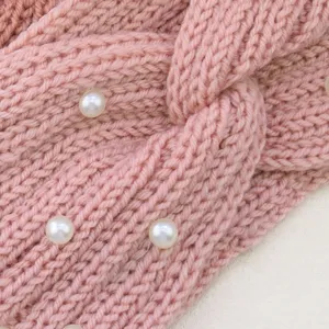 Dettaglio fascia in maglia con lana rosa morbida e perle bianche decorative.