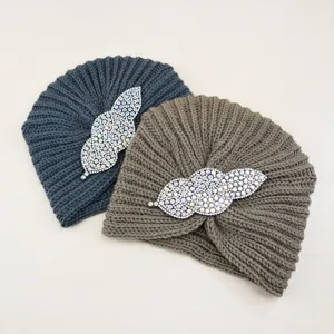 Close-up view of winter knitted turban hat with sparkling rhinestone leaf brooch detail.