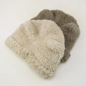 Detailopname van pluche harige winterse warme mutsen in beige en kaki, zachte stofkwaliteit.