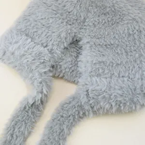 Gedetailleerd uitzicht van grijze pluche gebreide stof, warme wintermuts met lange zachte linten.