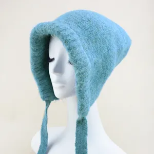 Close-up detail view of the soft blue knit woolen bonnet with hanging strap ties.