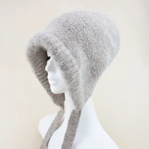 Close-up detail of a cozy solid color wool knit bonnet hat with cute hanging ties for winter.