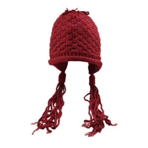 Primo piano dettagliato del berretto in maglia rosso scuro con motivo a quadri e trecce.