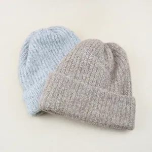 Close-up of soft knit winter beanies in grey and brown, showing cozy texture and warm fold.