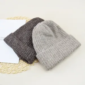 Detailed view of winter warm knitted beanies in dark brown and light grey colors.