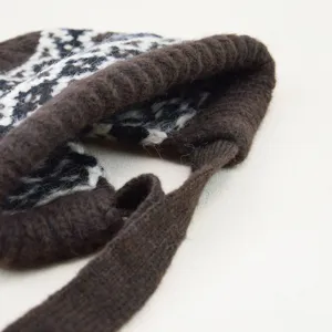Detailansicht der braun-weißen Jacquard-Strickmütze mit geflochtenen Bändern Textur.