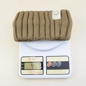 Knitted headband detail showing product weight, retro ribbed design with cute smiley tag.
