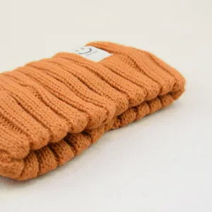 Close-up detail shot of the orange knit hairband showcasing the soft ribbed texture and cute smile label.