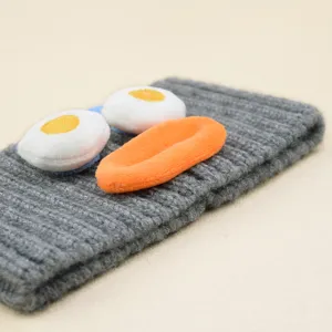 Graues Strickstirnband mit lustigen Plueschaugen und orangefarbenem Mund, perfekt fuer Yoga.