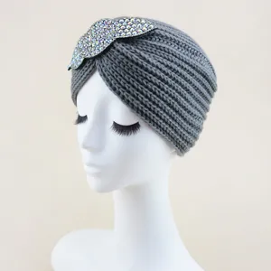 Close-up detail of the grey knitted turban hat featuring sparkling rhinestone leaf decor.