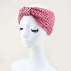 Close-up detail of a pink knitted headband with sparkling sequins and knotted bow design.