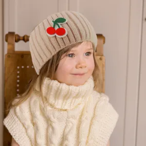 Dettaglio fascia bimba in maglia, accessorio capelli beige a costine con graziosa ciliegia.