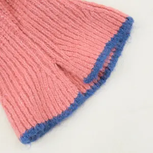 Detalle de gorro de punto acanalado rosa con borde de felpa azul y textura suave.