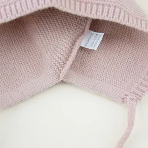 Gedetailleerd overzicht van het waslabel van de zachte gebreide baby muts met acrylmateriaal.