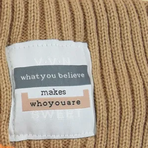 Nahaufnahme des braunen Strickstirnbands mit gemütlicher Textur und personalisiertem Etikett.