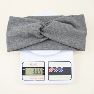 Graues gestricktes Twist-Stirnband Detailansicht auf Waage, weiches elastisches Haaraccessoire.