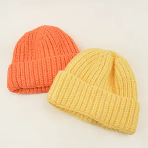 Closeup details of chunky knit children beanie in bright orange and yellow candy colors.
