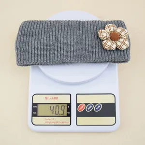 Grey knitted headband with plaid flower decor, soft elastic winter hair accessory.