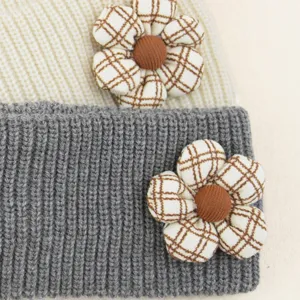 Detailed close-up of knit headband featuring cute plaid fabric flower and button center, cozy.