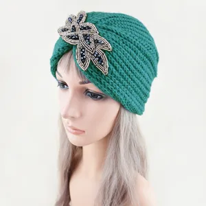 Vista detallada del gorro turbante de punto verde con decoracion floral de abalorios.