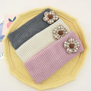 Close-up detail of knitted floral headbands in grey, beige, and pink with cute plaid flower accents.