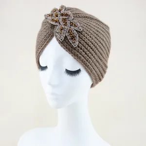 Vista detallada del gorro turbante de punto marrón con bordado de hojas de cuentas.