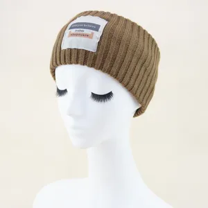 Braunes Strickstirnband Detailansicht, kuscheliges Winter Ohrenwärmer Zubehör mit Textetikett.