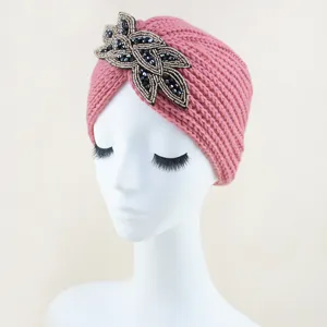 Vista detallada en primer plano del elegante turbante de punto rosa con abalorios decorativos.