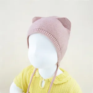 Gedetailleerd overzicht van roze gebreide baby muts met schattige oren en zachte touwtjes.