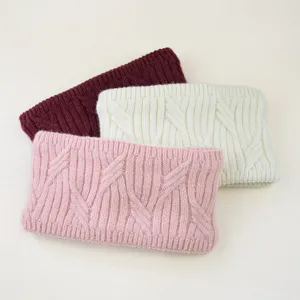 Detailed view of three thick knitted winter headbands in pink, white, and burgundy.