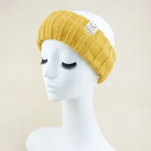 Detailed close-up view of yellow knitted hair headband featuring a cute smiley tag for yoga use.