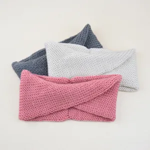 Detailaufnahme von drei gestrickten Twist-Haarbändern in Rosa, Weiß und Grau für den Winter.