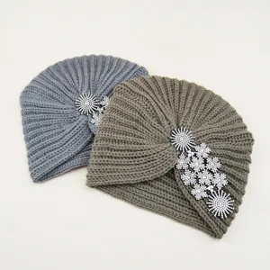 Detailed view of cozy winter knitted turban hats with sparkly rhinestone flower embellishments.