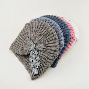 Detailed close-up of stacked winter knitted turbans with elegant crystal rhinestone brooch.