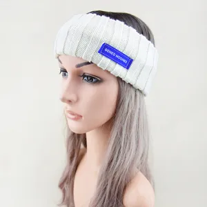 Gedetailleerd aanzicht van een witte gebreide haarband met blauw label, zachte woltextuur.