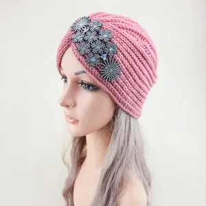 Close-up detail of the pink knitted turban hat featuring sparkling rhinestone flower crystal decor.