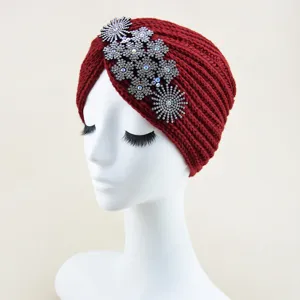 Close-up detail of a red knitted turban hat decorated with sparkling crystal rhinestones.