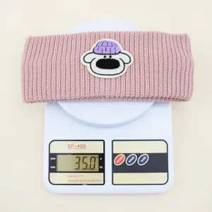 Primo piano dettagliato della fascia in maglia rosa con patch di cartone, accessorio invernale.