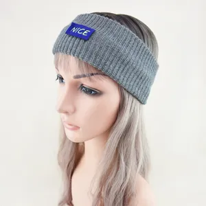 Grey knitted headband detail view, winter warm hair accessory with blue NICE label patch.