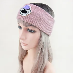 Vista dettagliata della fascia in maglia rosa con simpatica toppa di orsetto e tessitura morbida.