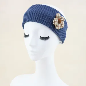 Detailed blue knitted headband close up, cozy ear warmer with cute plaid fabric flower ornament.